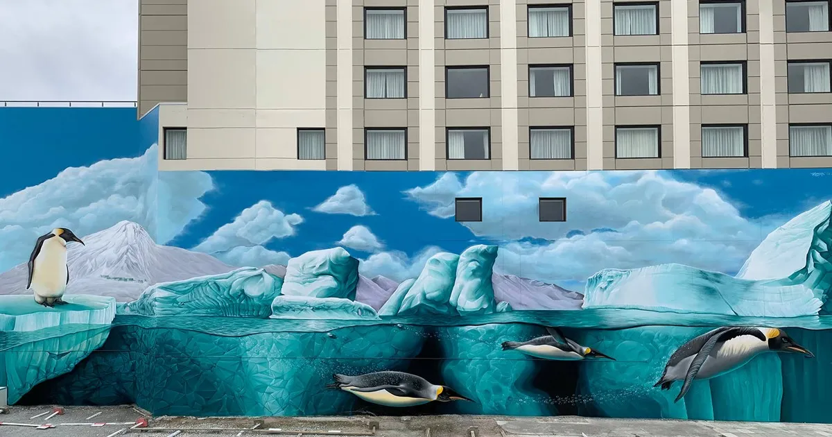 A street mural of penguins and icebergs painted on a wall below an apartment building
