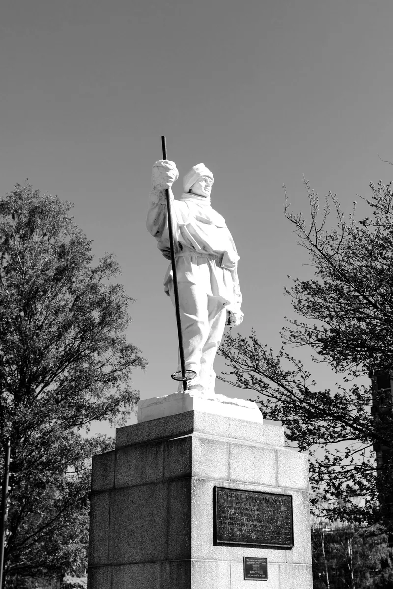 A white marble statue of a polar explorer on a stone plinth