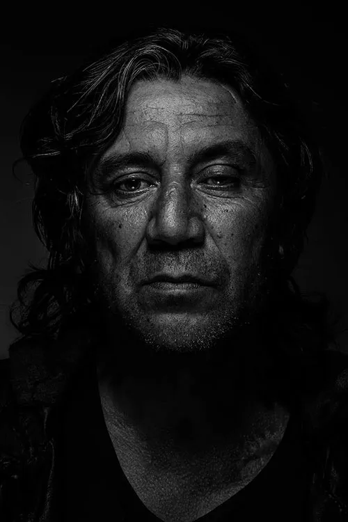 Black and white portrait of a man with long dark hair, lit from one side